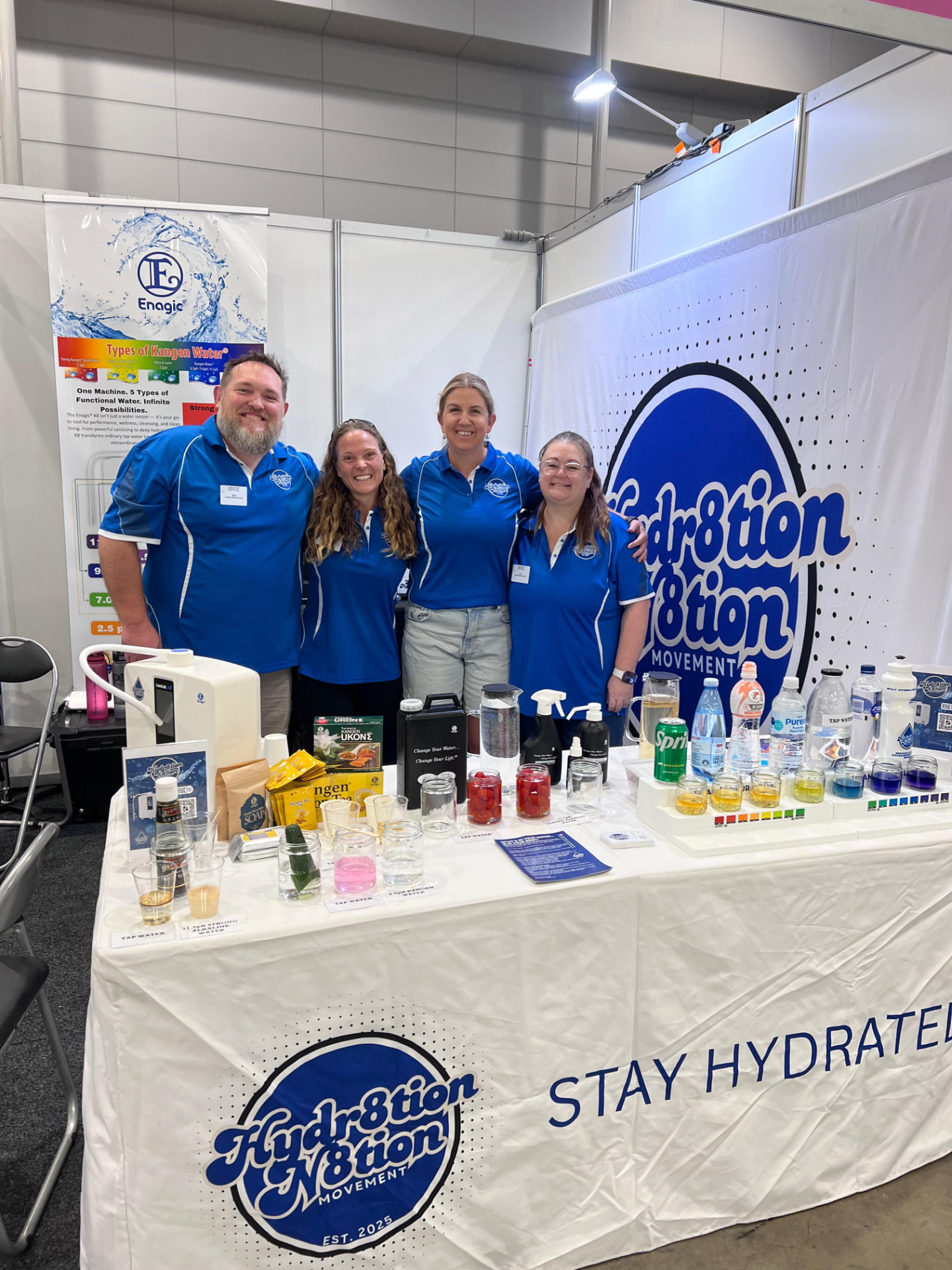 Four Hydr8tion N8tion team members standing behind their branded exhibition table